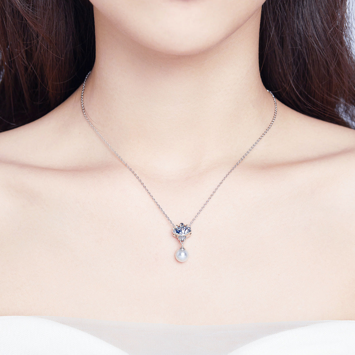 Necklace with a pendant featuring a heart and pearl on a plain background