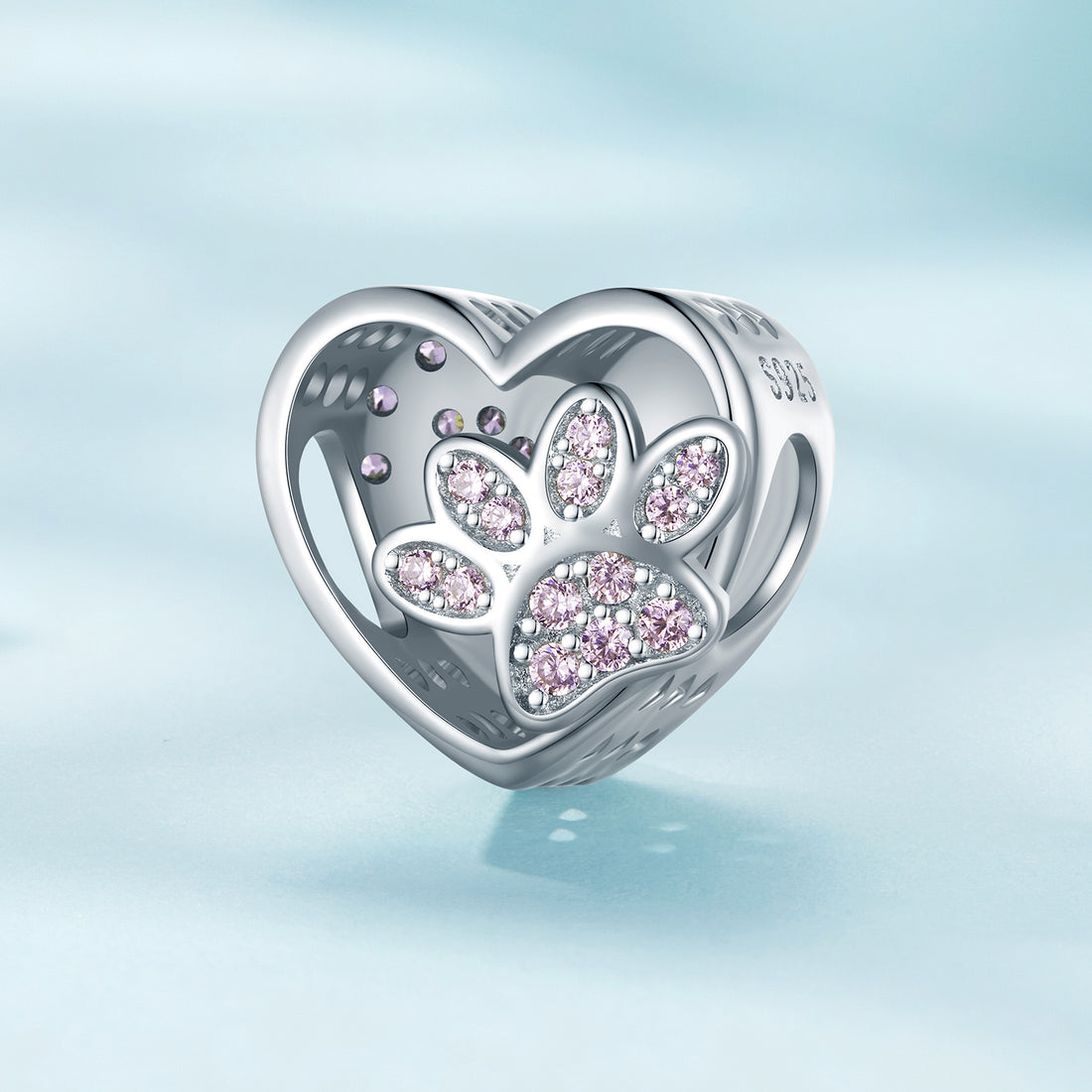 Heart-shaped charm with paw prints and pink stones on a light blue background