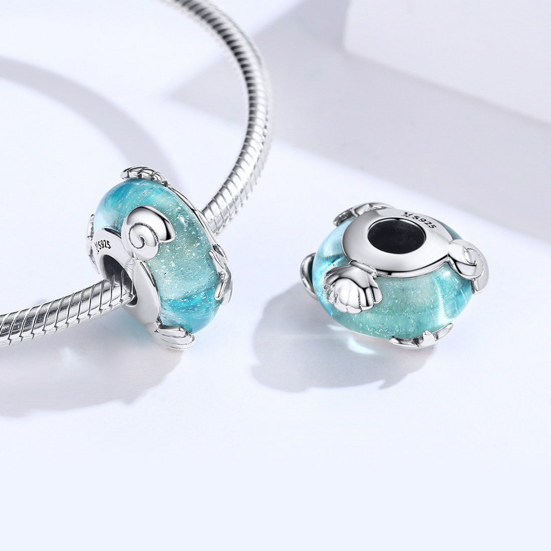 Blue glass charm with silver star design on a light gray background