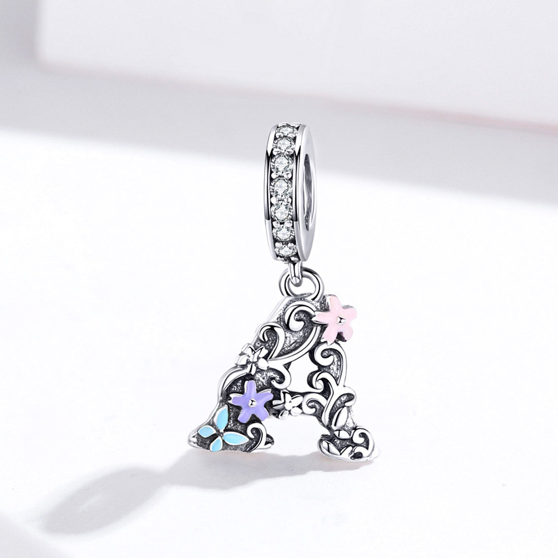 Silver pendant with floral designs and colorful stones on a white background