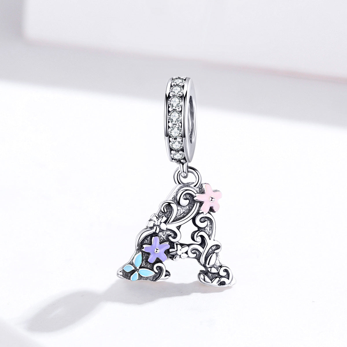 Silver pendant with floral designs and colorful stones on a white background