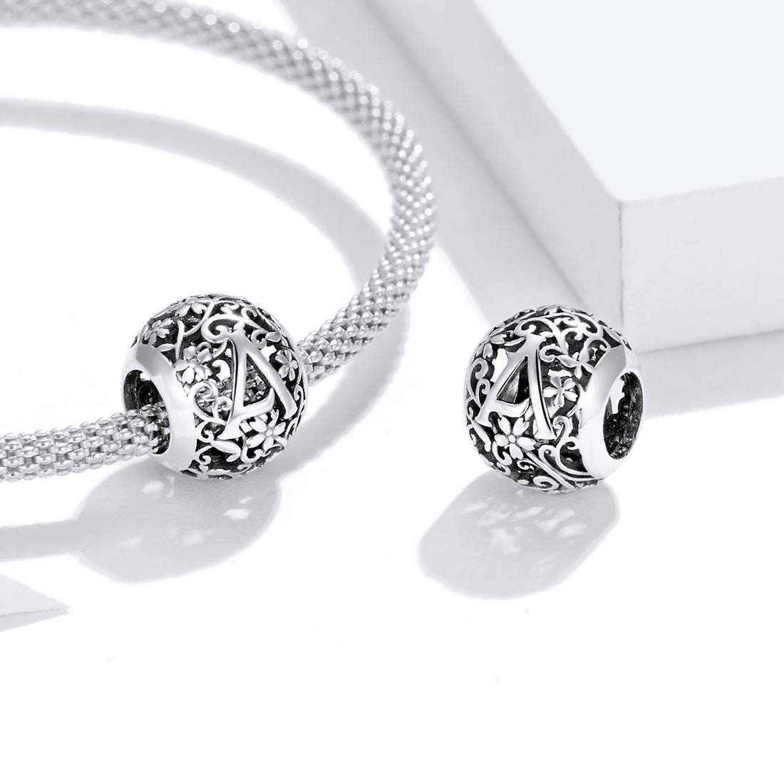 Silver charm with letter 'A' and floral designs on a white background