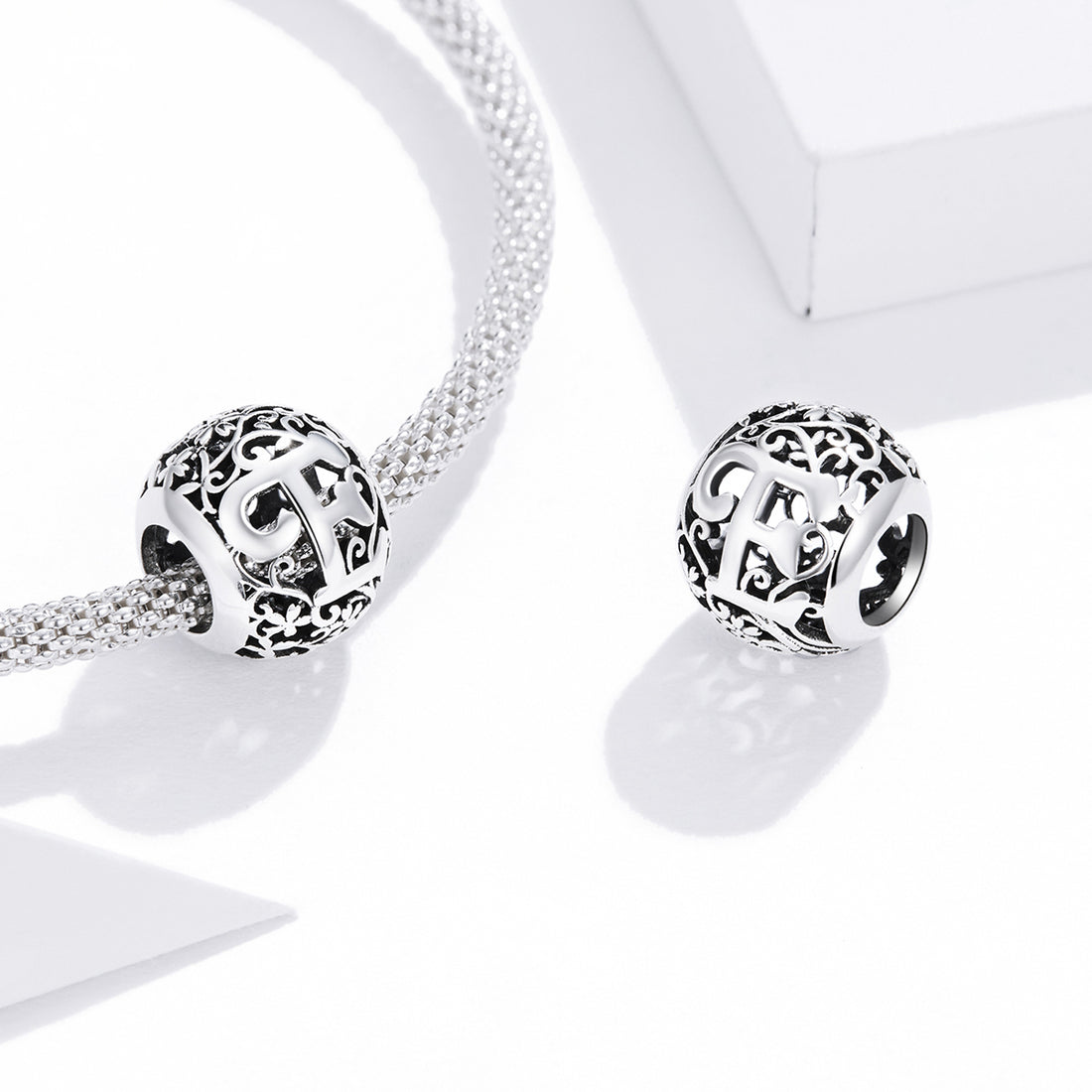 Silver charm with intricate design and letter 'E' on a white background