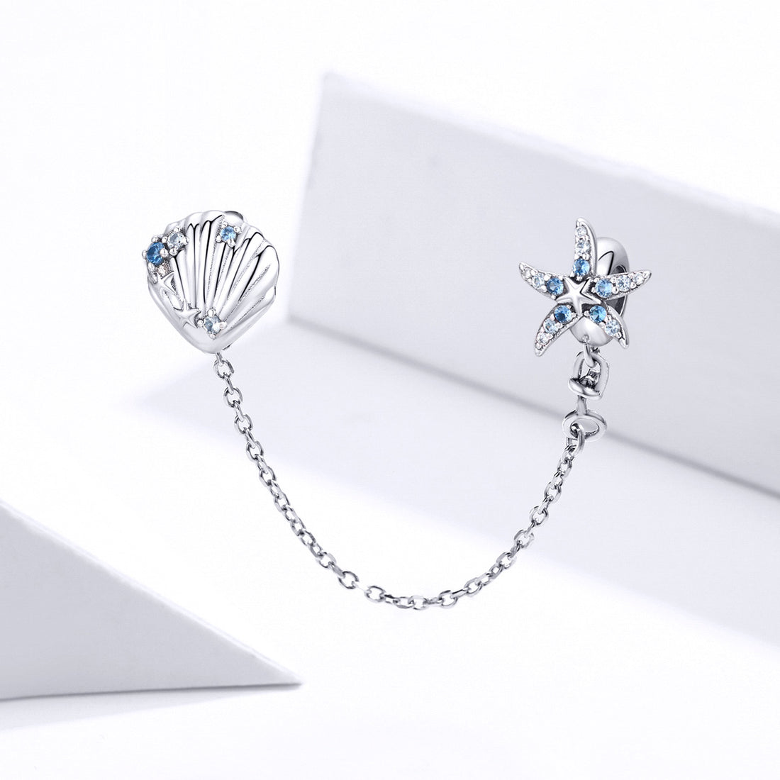 Silver earrings with starfish and shell design on a white background