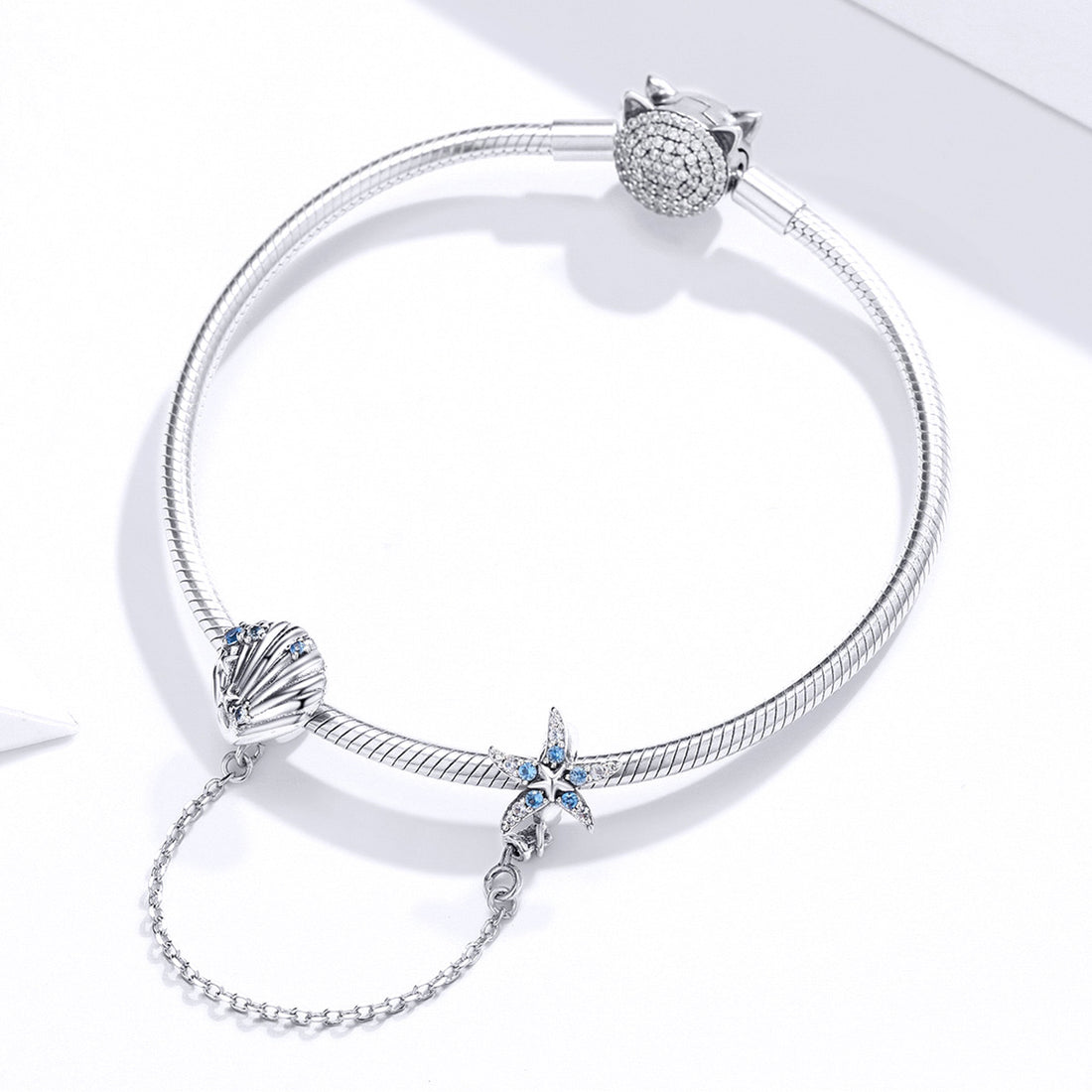Silver earrings with starfish and shell design on a white background
