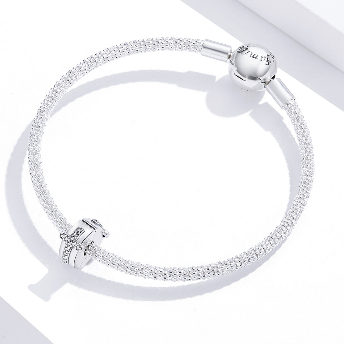 Silver cross charm with clear stones on a white background