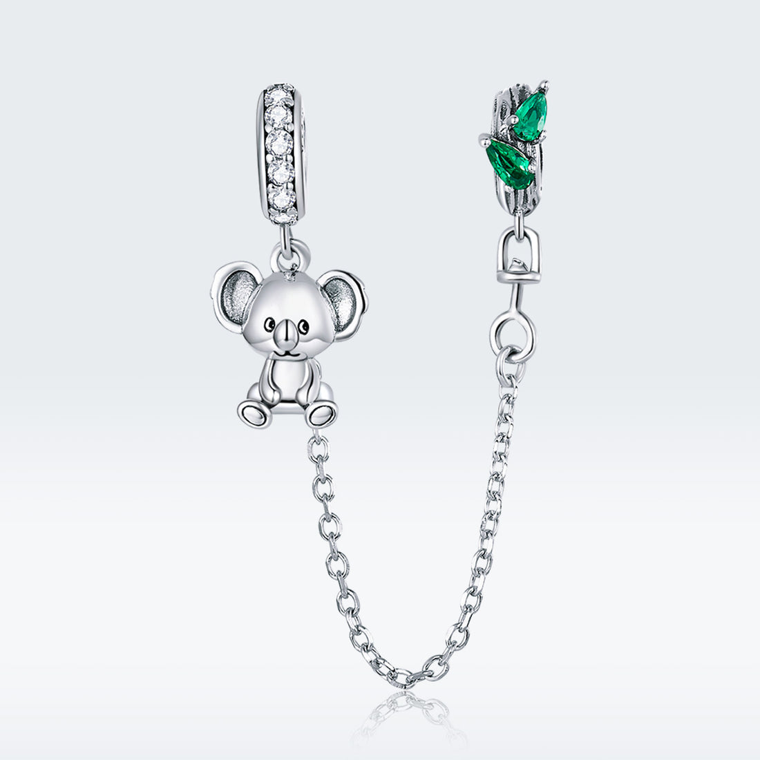 Silver teddy bear charm with a chain and green gemstone on a white background