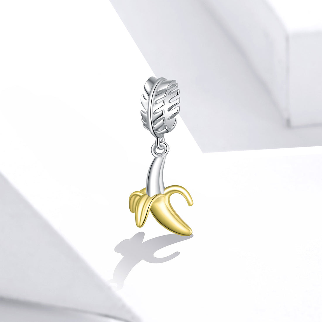 Silver and gold banana-shaped charm on a white background
