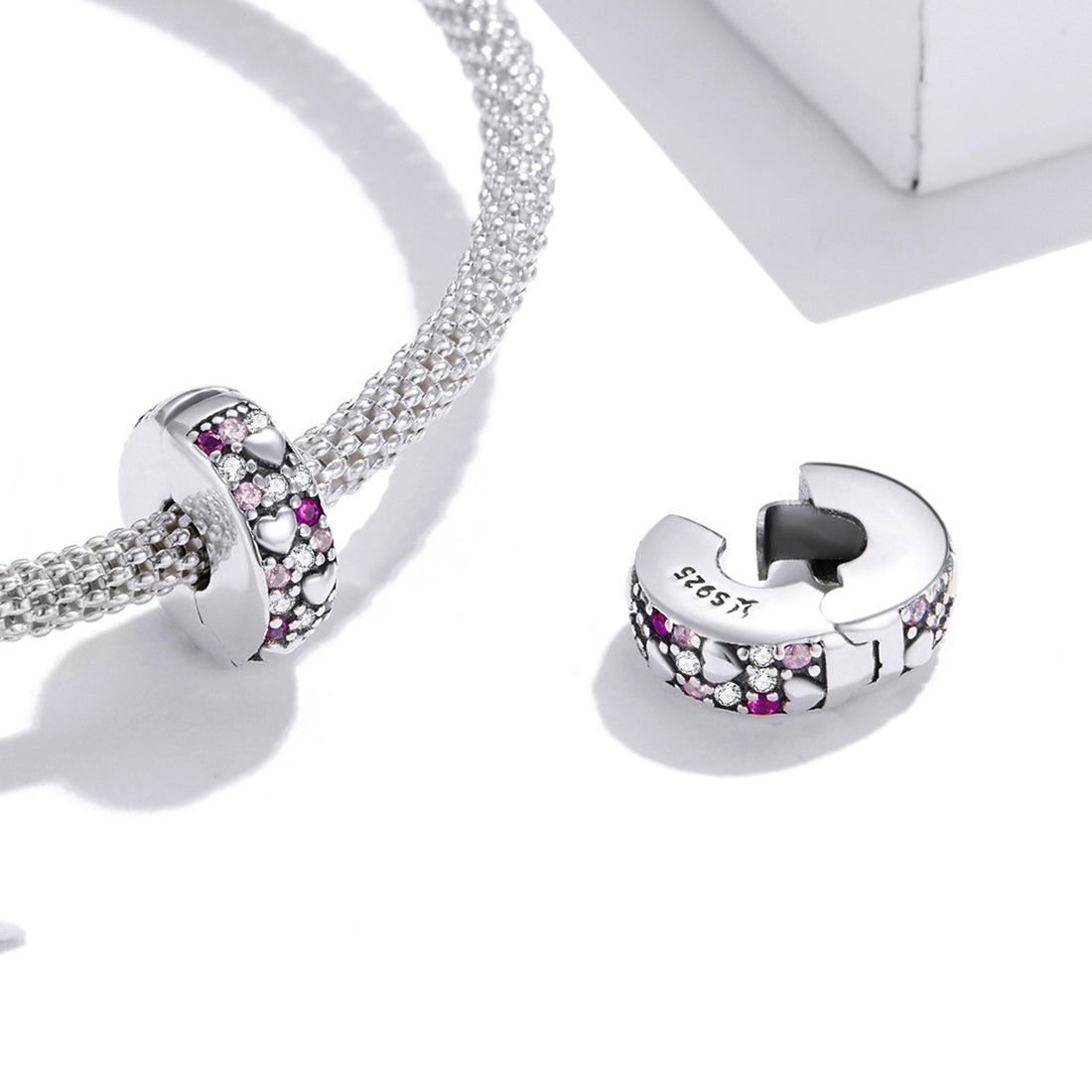 Silver charm with pink and clear stones on a light gray background