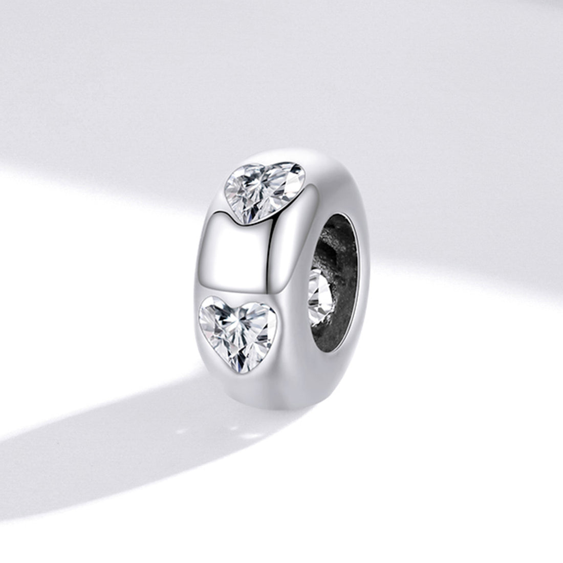 Silver charm with heart-shaped and round cut gemstones on a white background