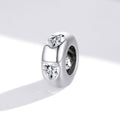 Silver charm with heart-shaped and round cut gemstones on a white background