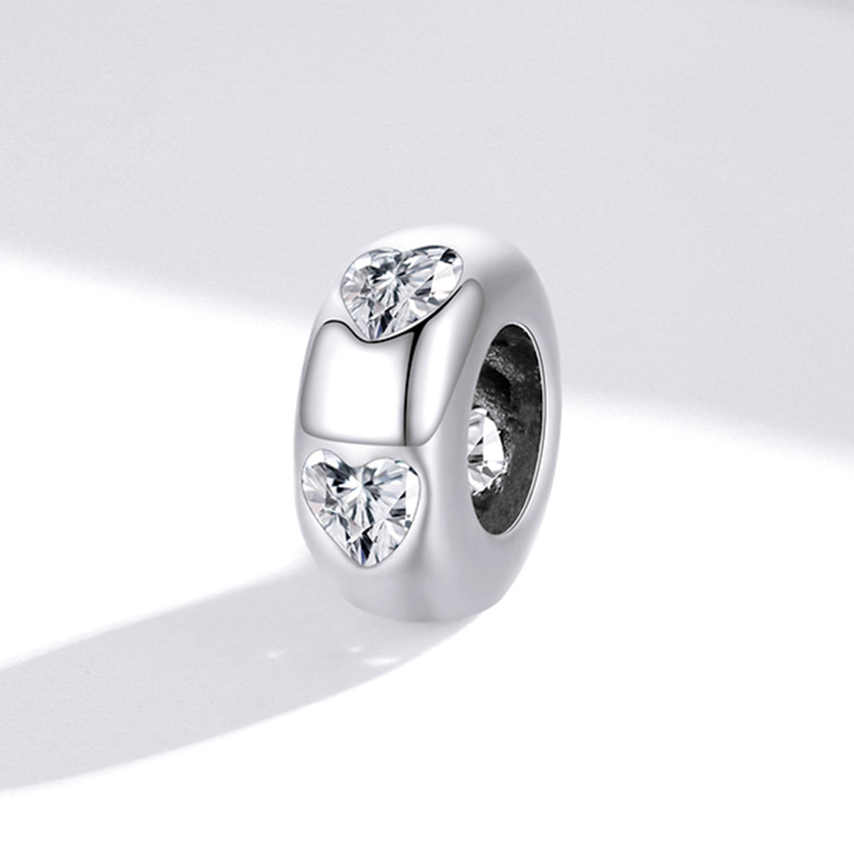 Silver charm with heart-shaped and round cut gemstones on a white background