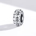 Silver jewelry charm with intricate heart design on a white background