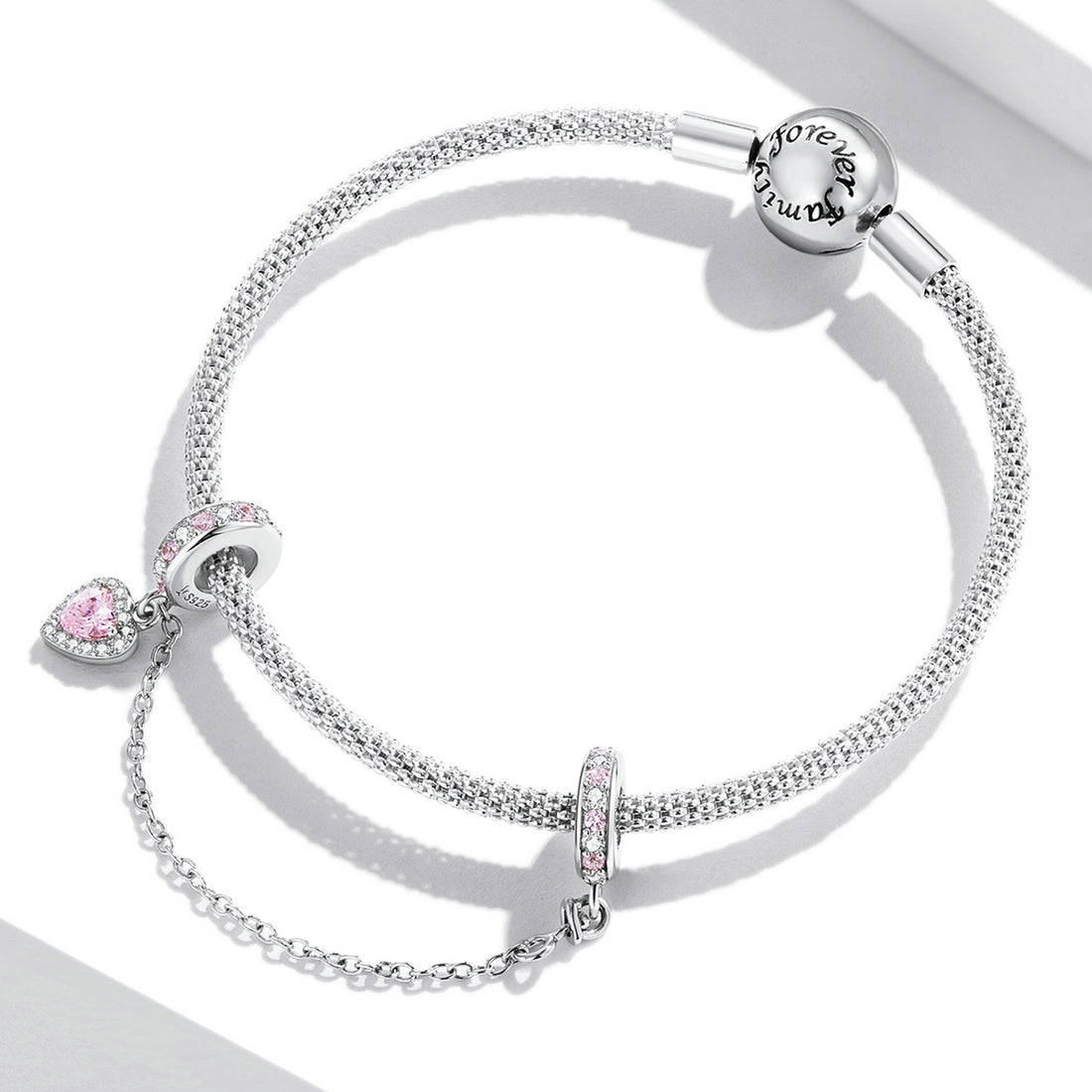 Silver charm with pink stones on a white background