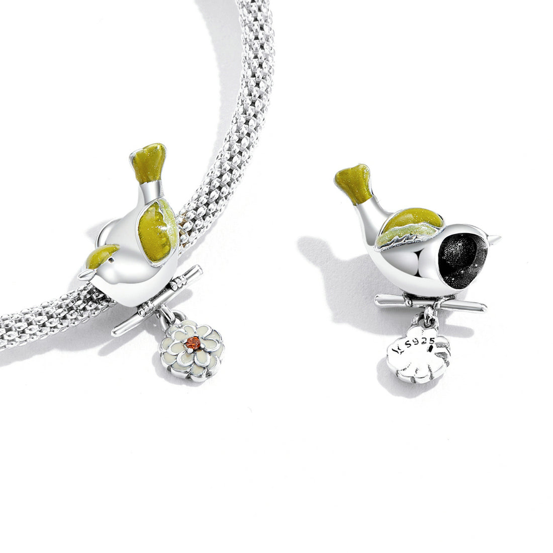 Silver charm shaped like a bird with green accents on a white background