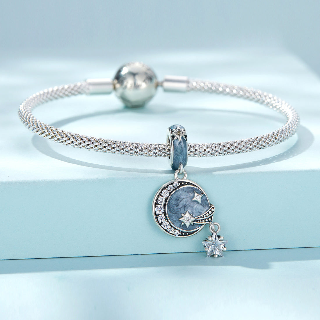 Silver charm with star and moon design on a white background