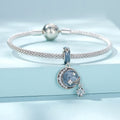 Silver bracelet with a moon and star charm on a light blue background
