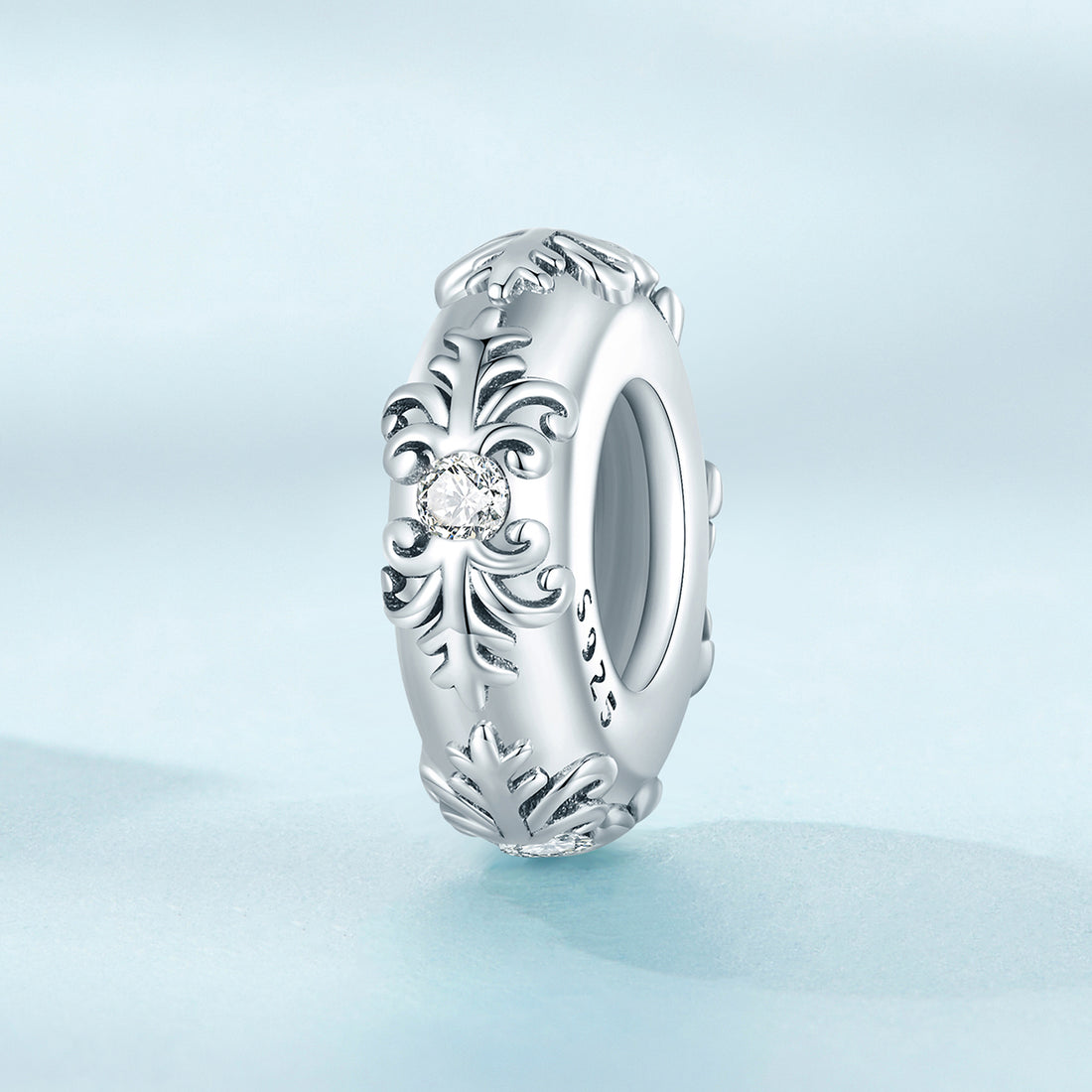Silver ring with intricate design on a light blue background