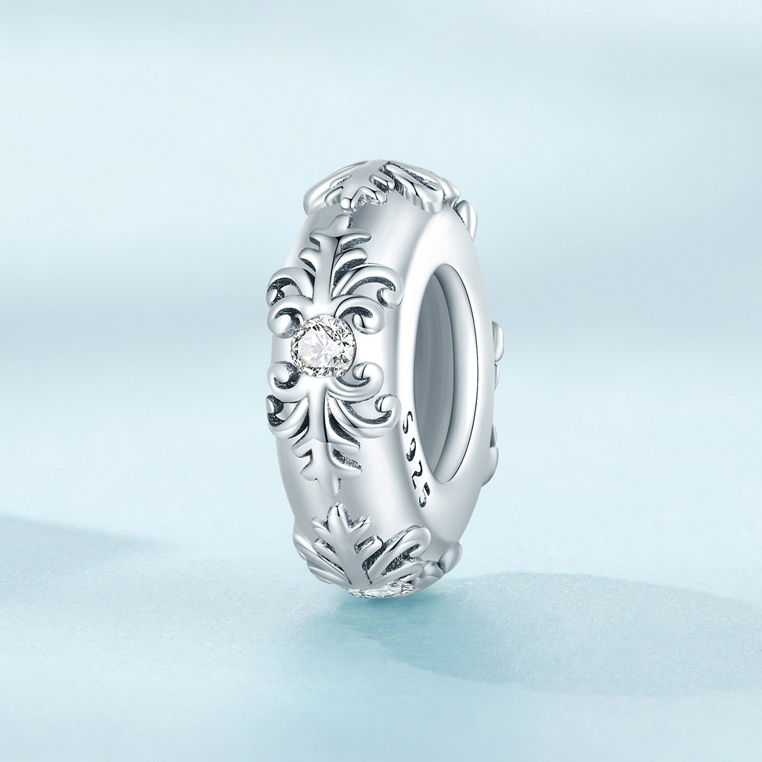 Silver ring with intricate design on a light blue background