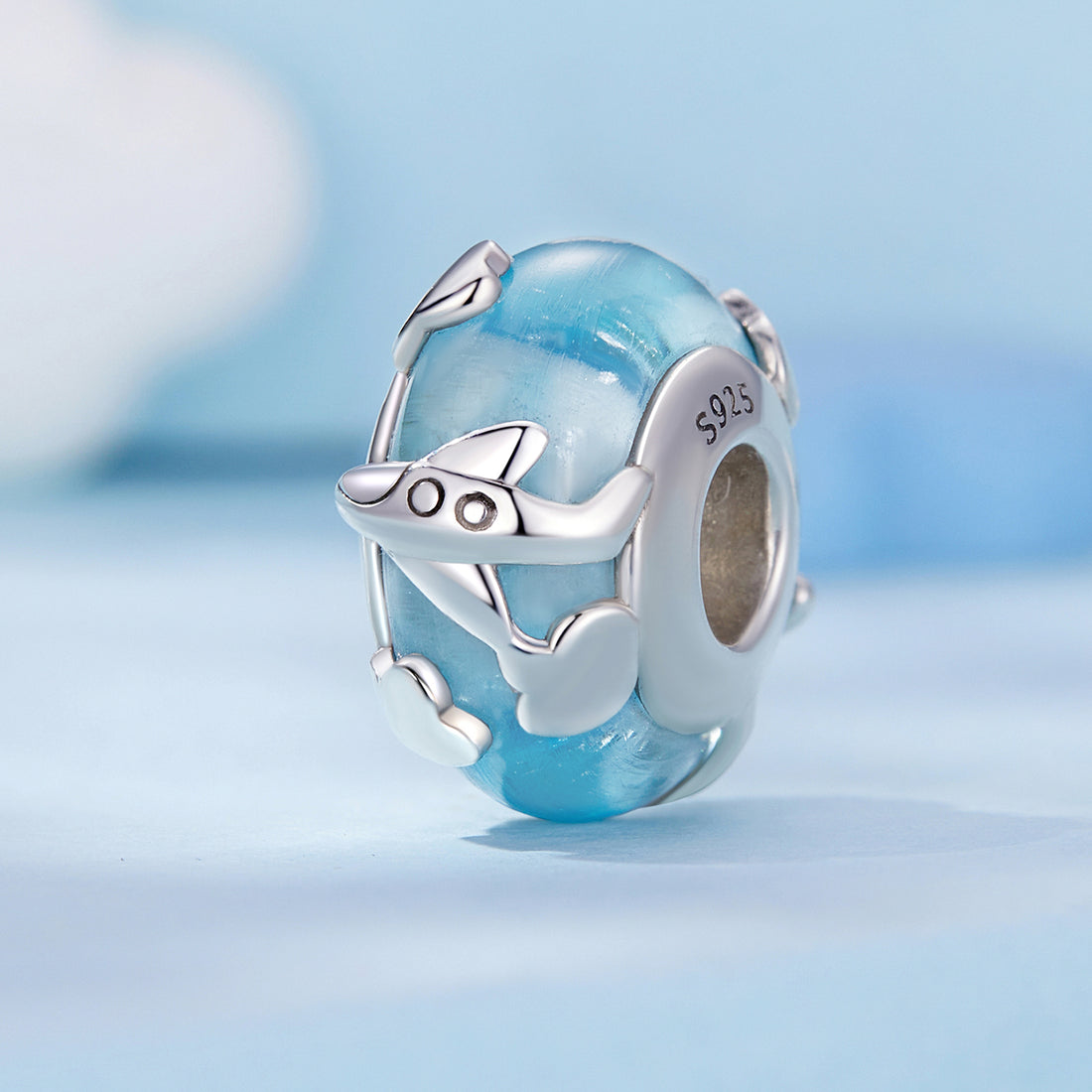 Silver charm with blue glass bead on a light blue background