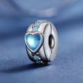 Silver charm with a blue heart-shaped gem on a blue background