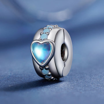 Silver charm with a blue heart-shaped gem on a blue background
