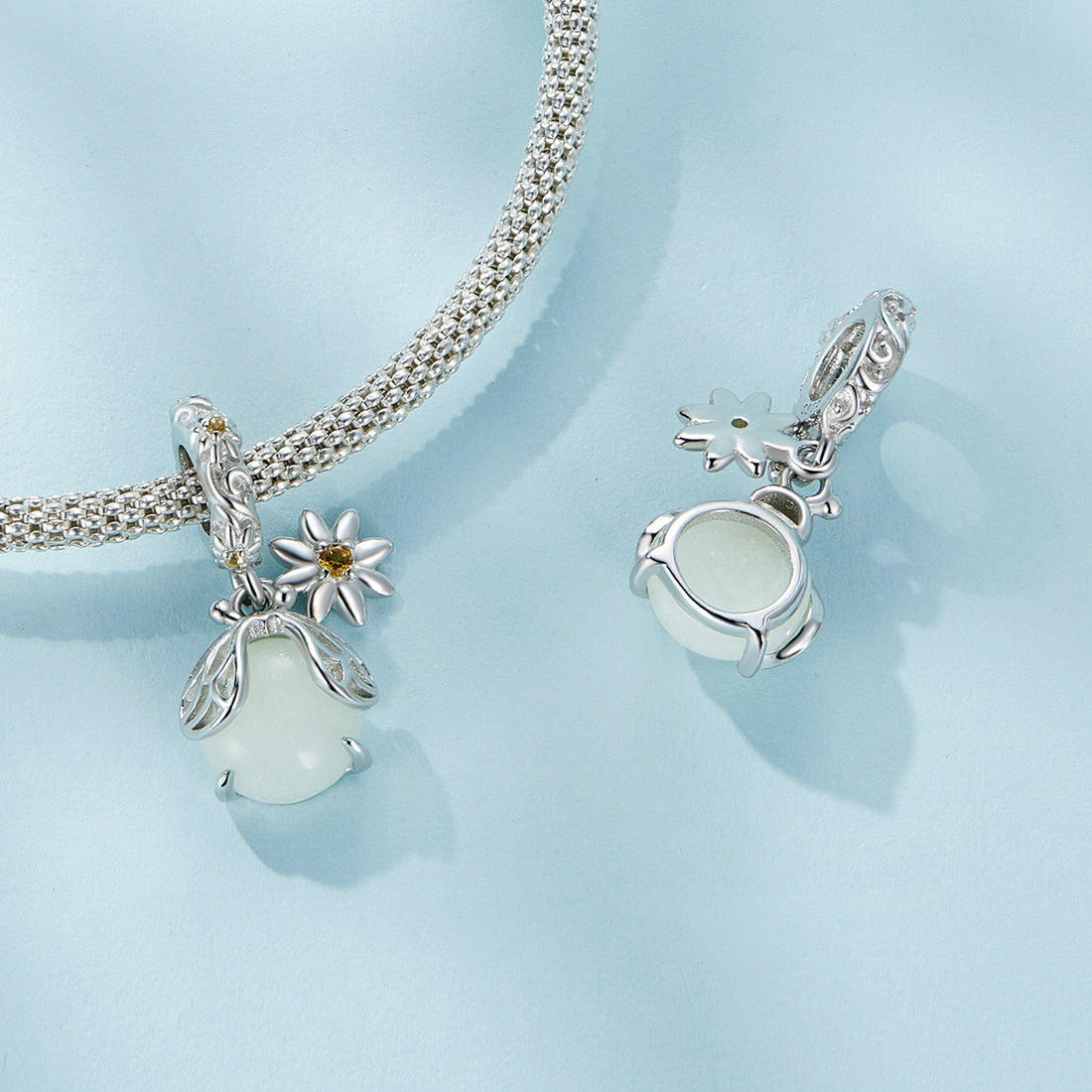 Silver charm with floral design and gemstones on a white background