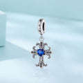 Silver cross-shaped pendant with a blue gemstone on a light blue background