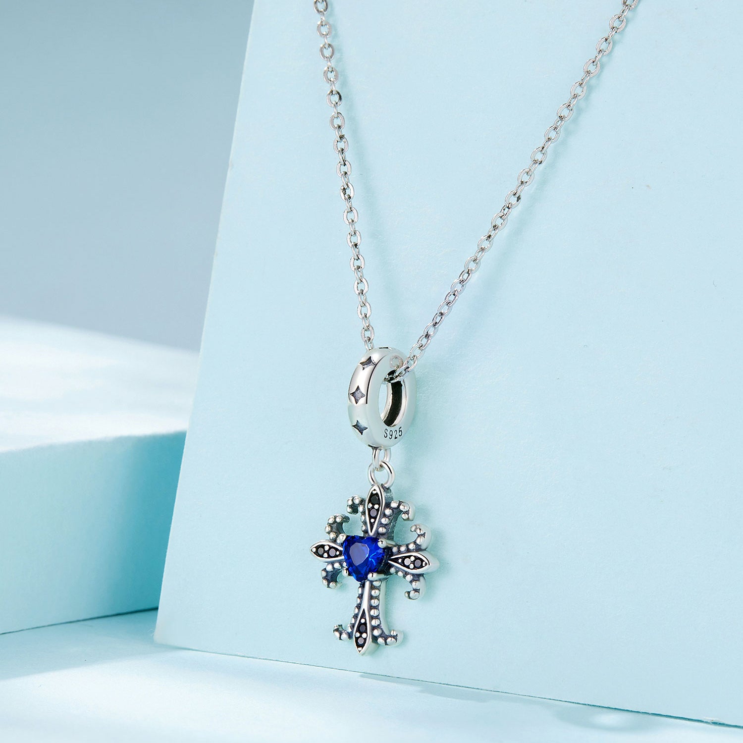 Silver necklace with a blue gemstone pendant on a light blue background