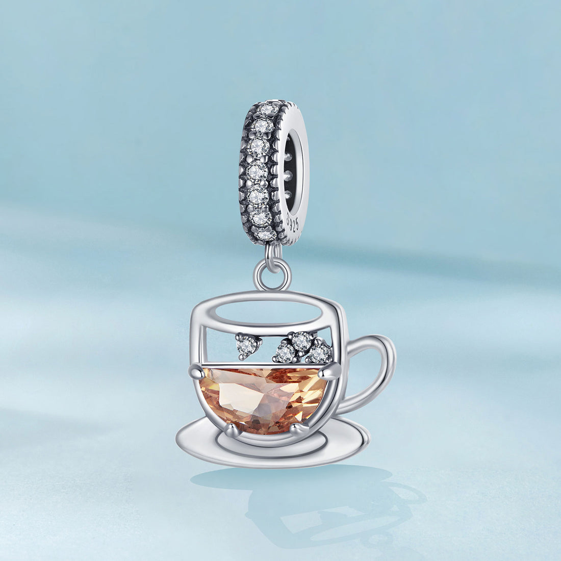 Silver teacup charm with gemstones on a light blue background