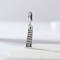 Silver charm shaped like the Leaning Tower of Pisa on a light gray background