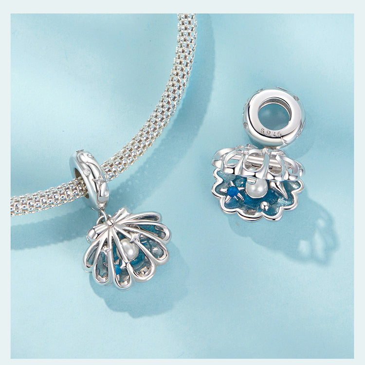 Silver shell charm with blue interior on a light blue background