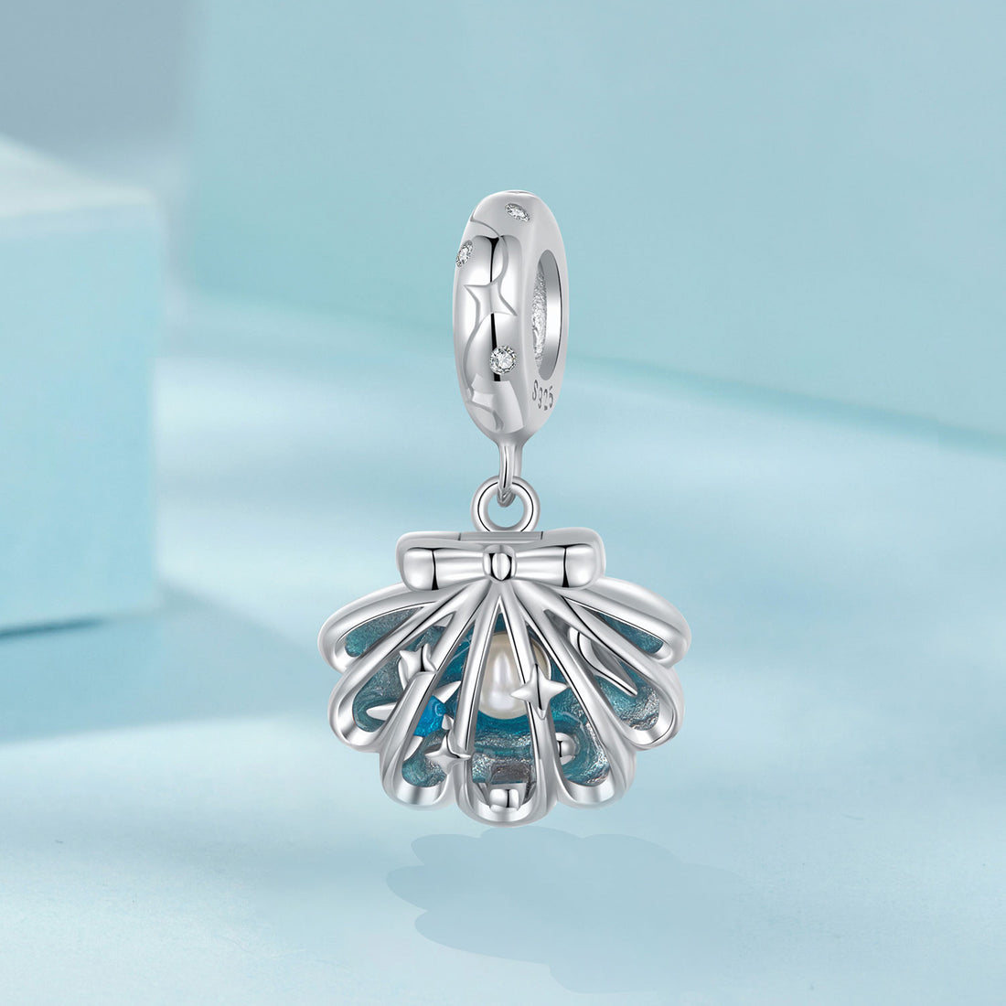 Silver shell charm with blue interior on a light blue background