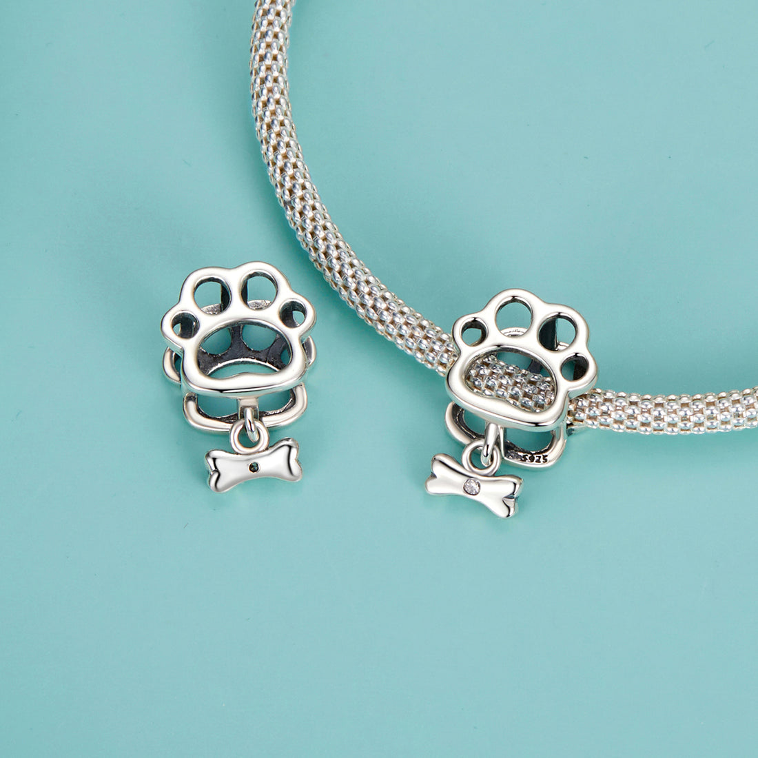 Silver paw print charm with a bone pendant on a pastel background