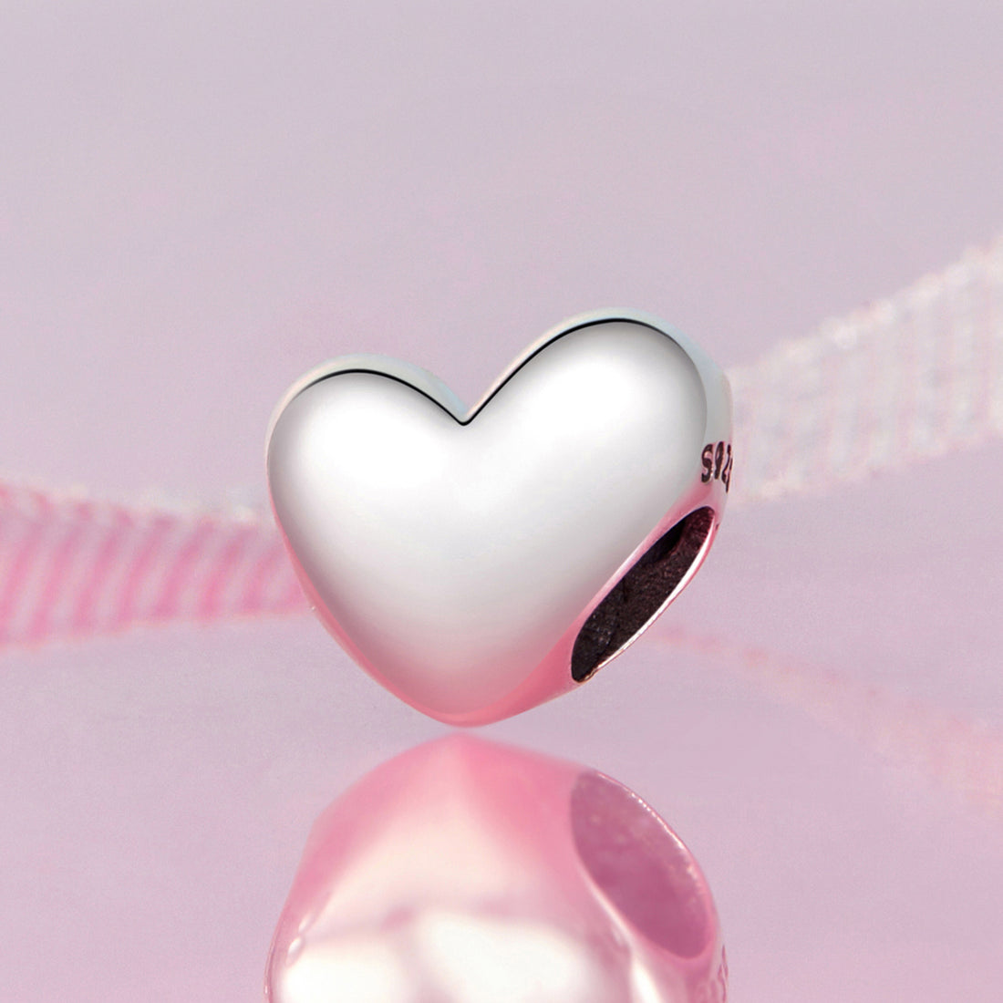 Heart-shaped silver charm on a pink background