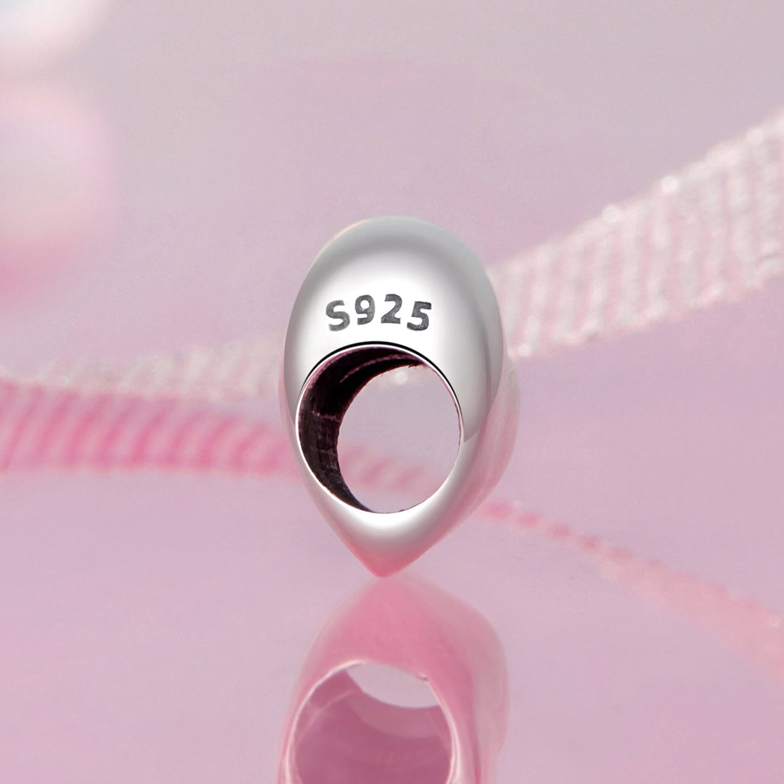 Heart-shaped silver charm on a pink background