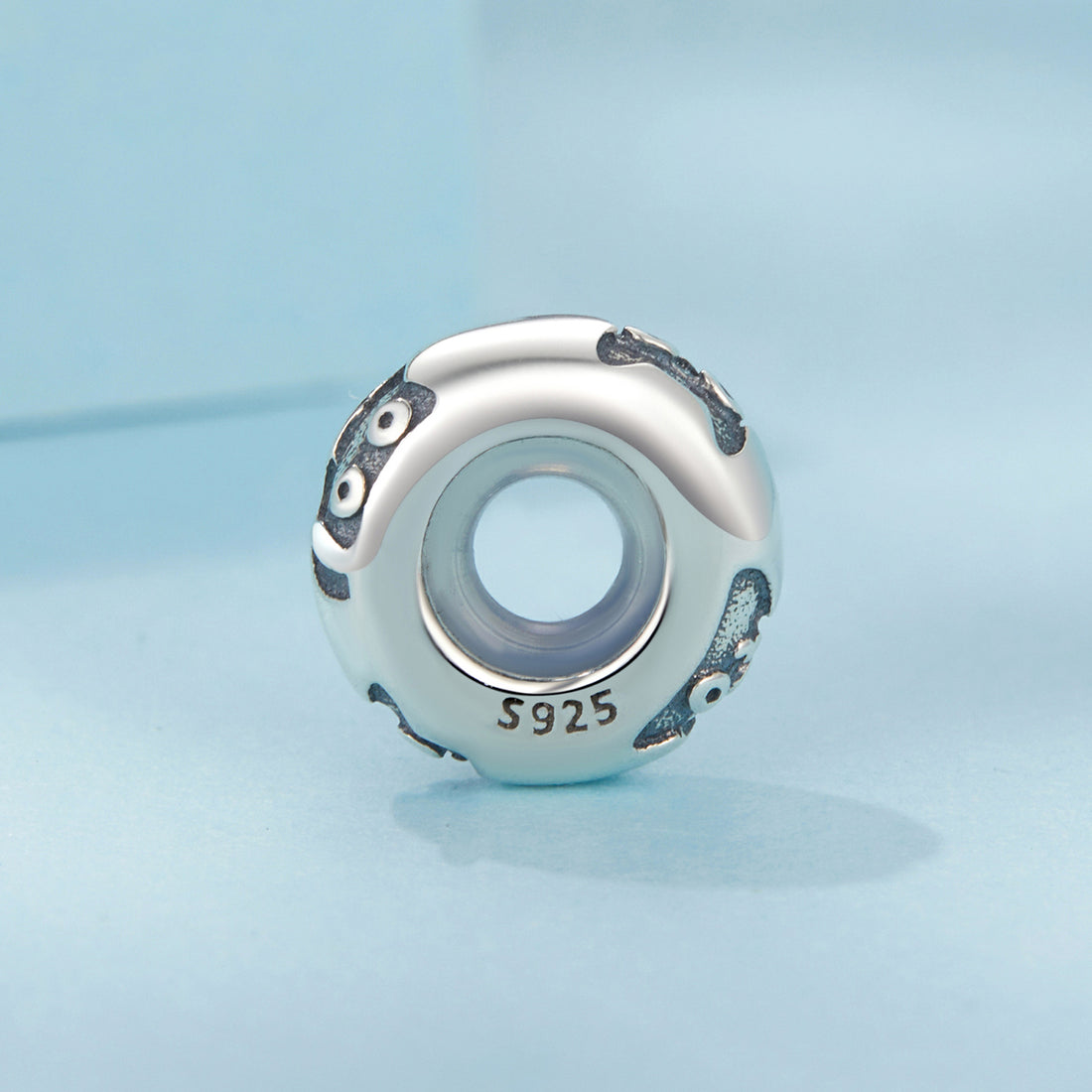 Silver charm with blue accents on a light blue background