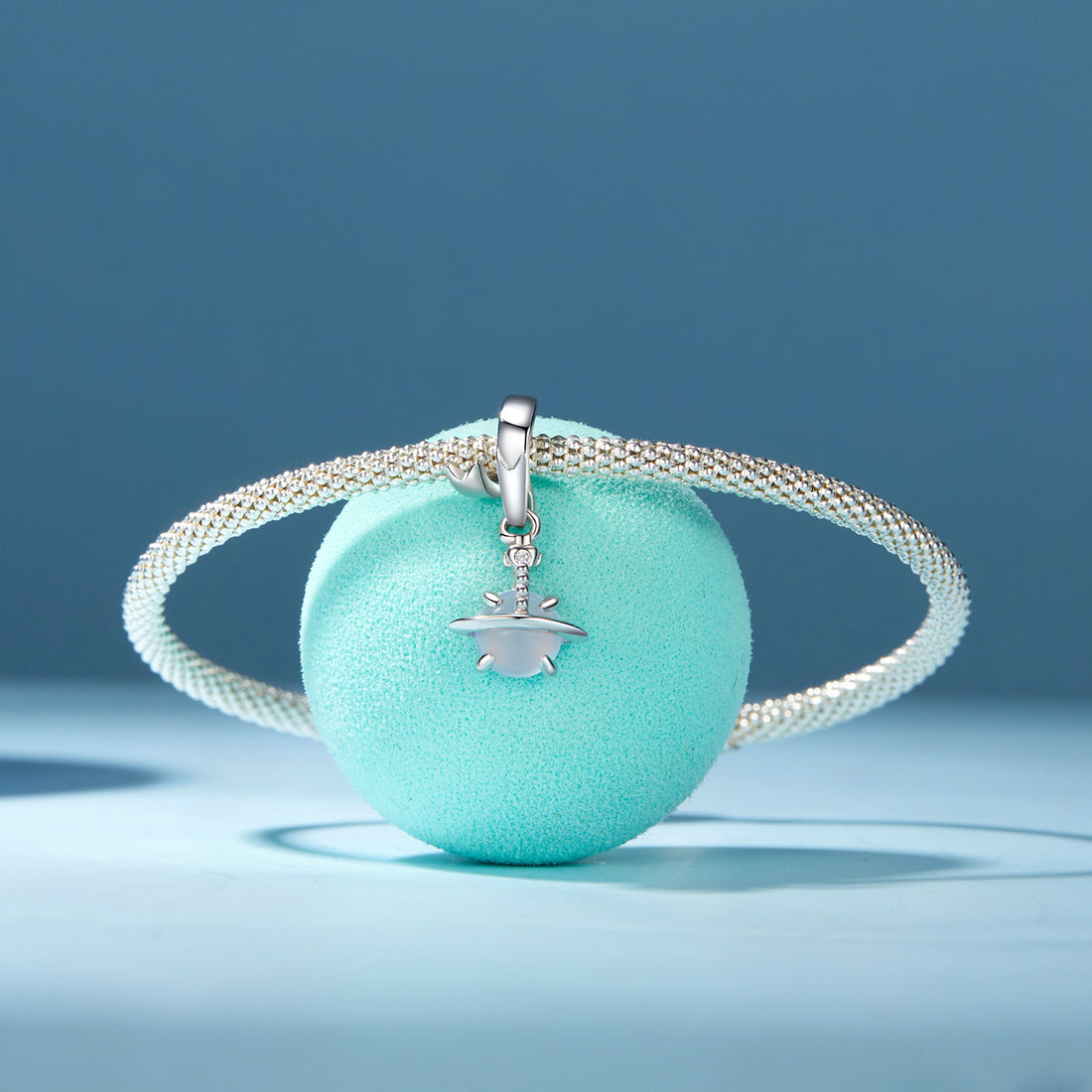 Silver charm with a white bead on a white background