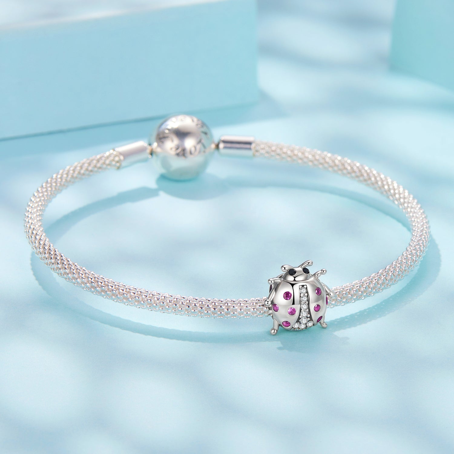 Silver bracelet with a ladybug charm on a light blue background