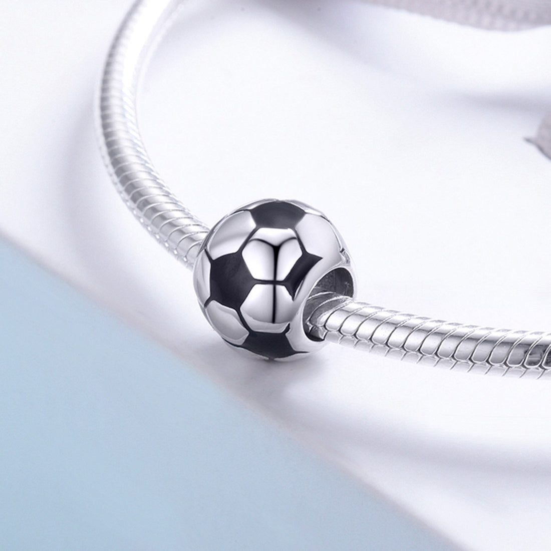 Silver soccer ball charm on a light gray background