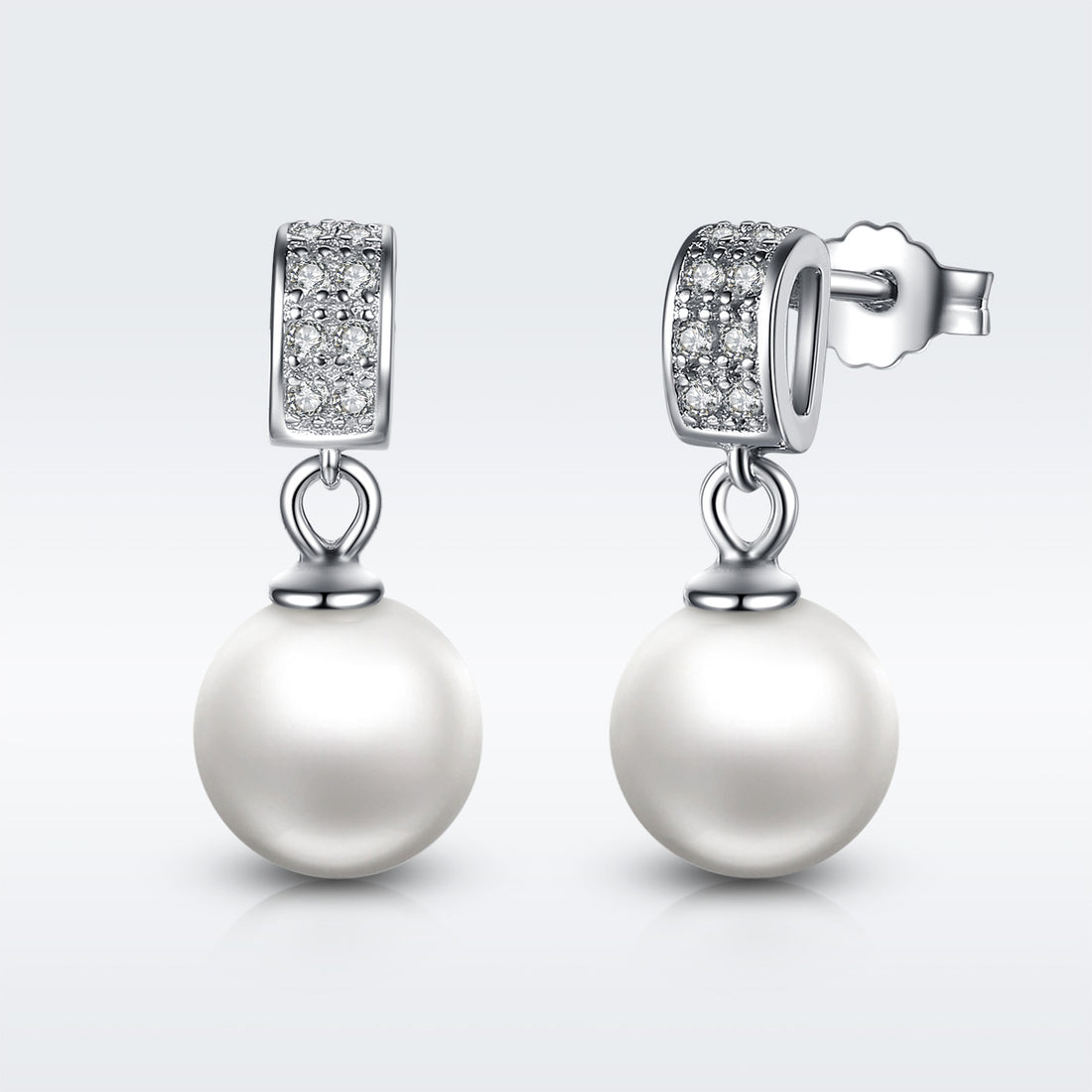 Pearl earrings with diamond accents on a light gray background