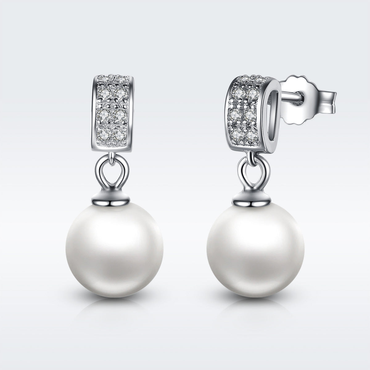 Pearl earrings with diamond accents on a light gray background