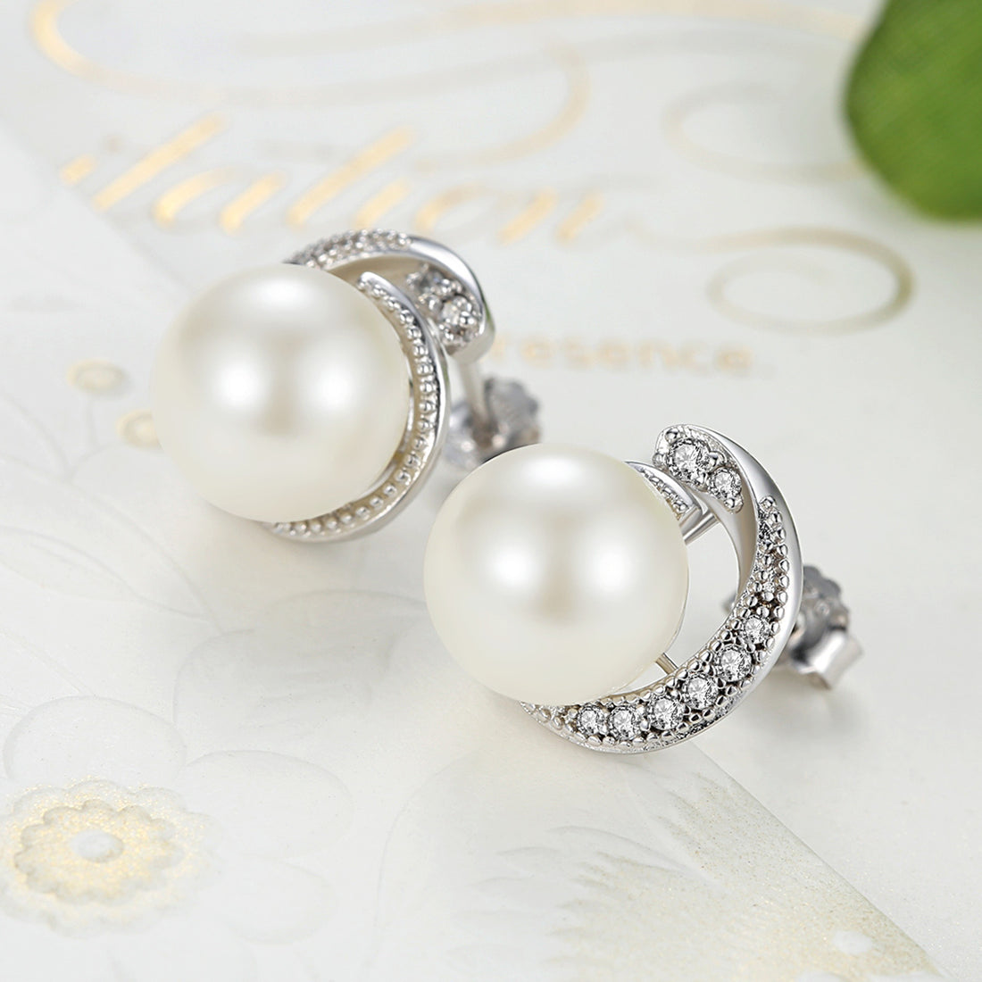 Pearl stud earrings with silver and diamond accents on a white background