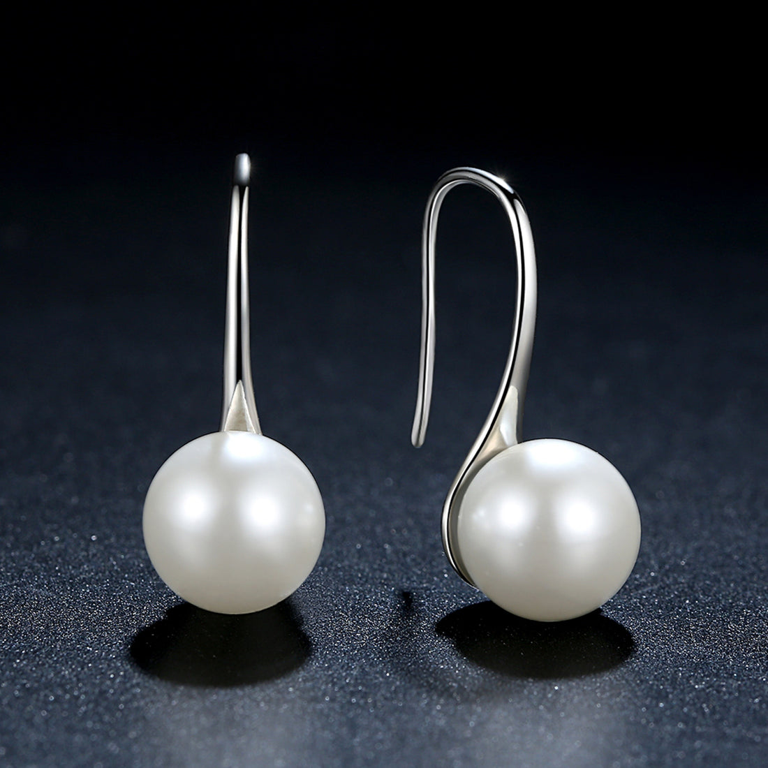 Pair of silver earrings with pearl-like spherical ends on a white background