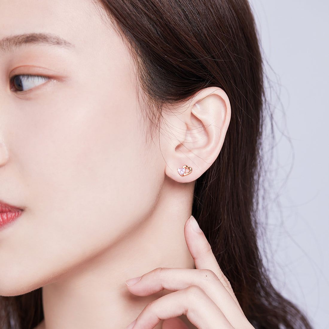 Heart-shaped earrings with pink gemstones and rose gold frames on a white background