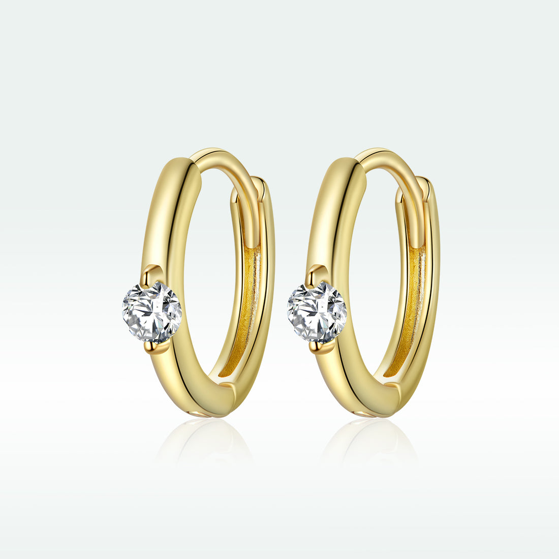 Gold hoop earrings with clear gemstones on a white background