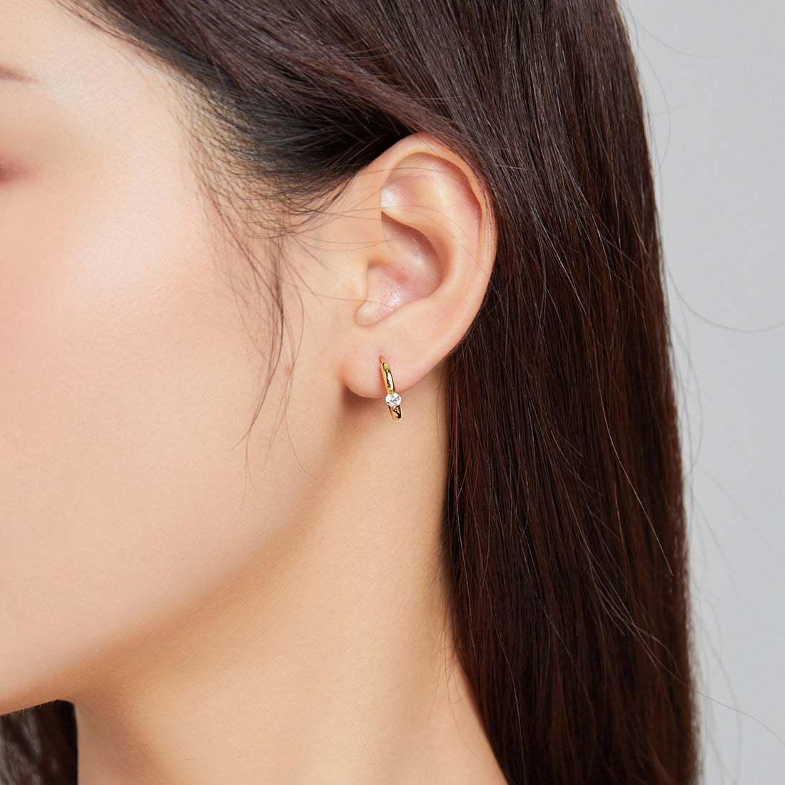 Gold hoop earrings with clear gemstones on a white background