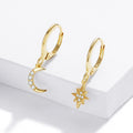 Gold hoop earrings with moon and star charms on a white surface