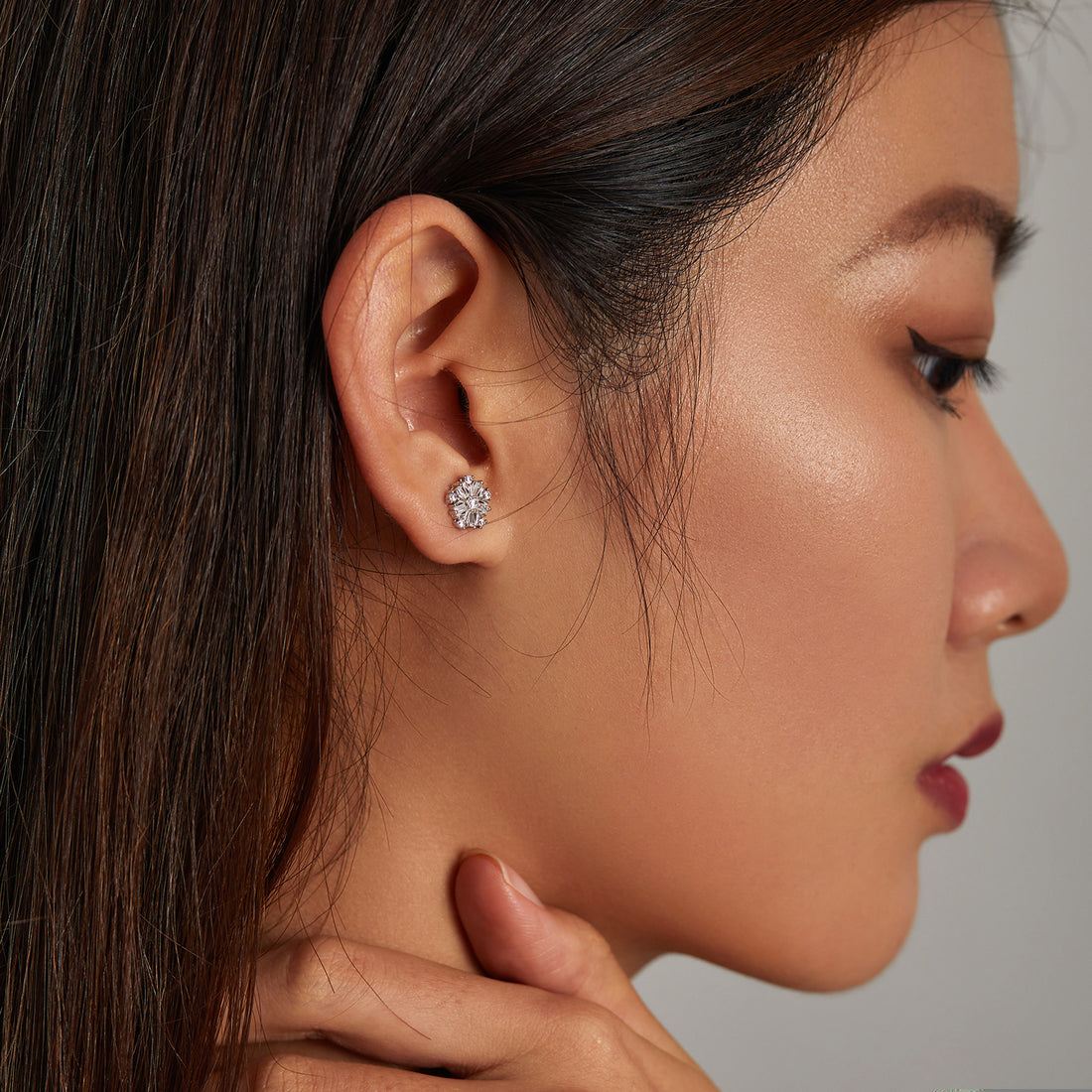 Pair of silver earrings with clear gemstones on a white background