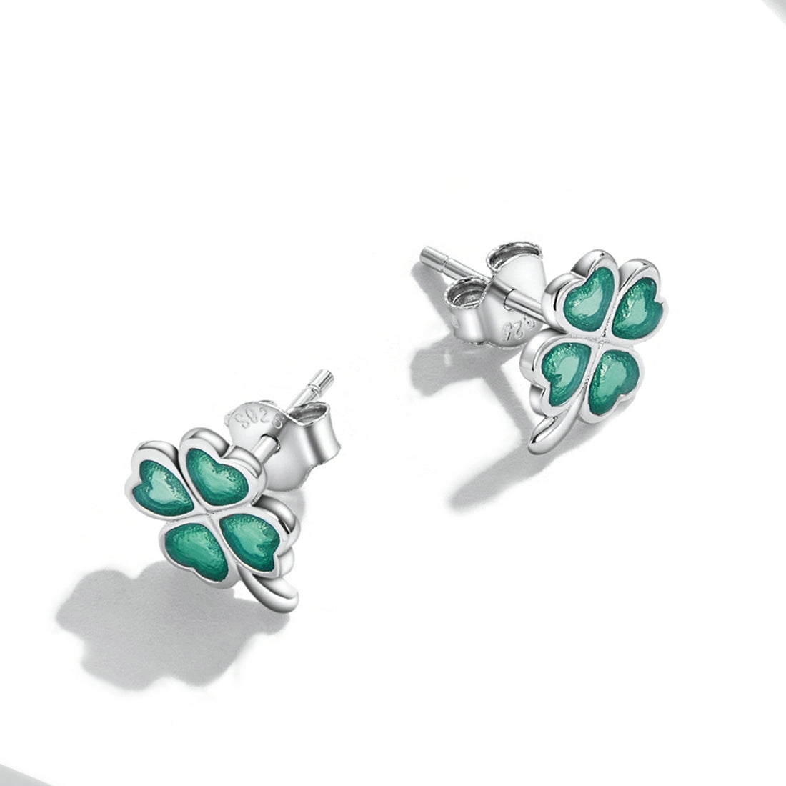 Pair of four-leaf clover earrings with green gemstones on a white background